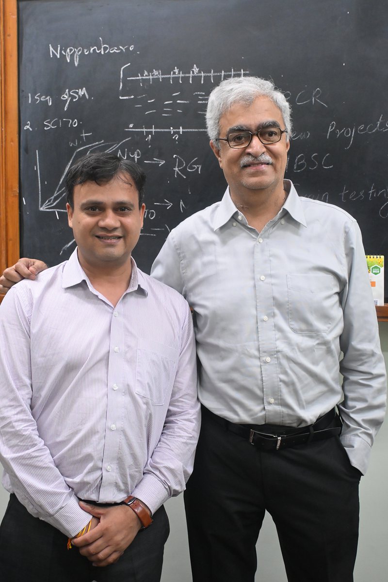 Two researchers in front of a blackboard of project notes